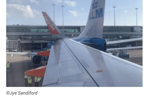 The wing of an EasyJet aircraft colliding with the tail of a KLM aircraft near the boarding gates, as seen from the EasyJet pasenger window.