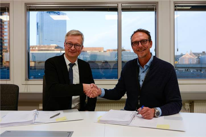 Mr. Oliver Ossege, Regional Sales Director of FREQUENTIS and Mr. Anders Kirsebom, CEO of Avinor Air Navigation Services. They are sat at a desk, shaking hands and smiling at the camera.